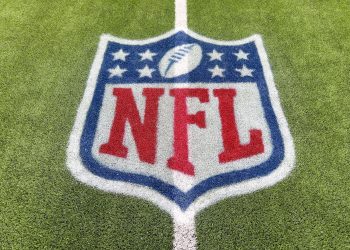 2YMNYRT An NFL logo on a green artificial grass football field line in full color.